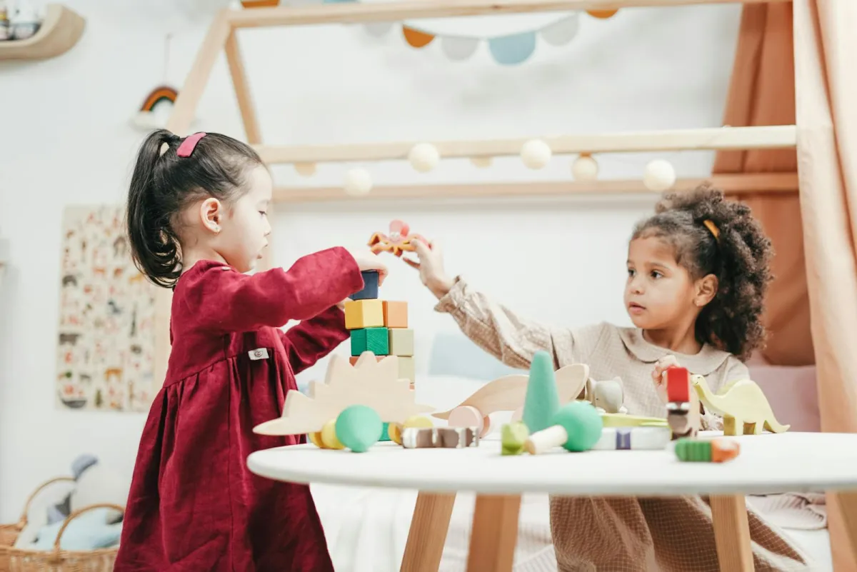 Zwei Kleinkinder spielen gemeinsam mit Holzklötzen