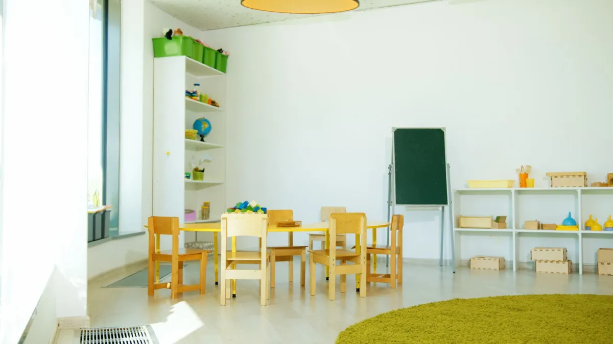 Heller Gruppenraum mit kleinen Holztischen und Kinderstühlen